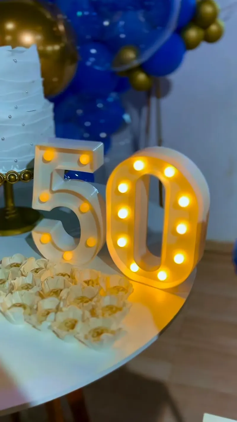 Letras luminosas 50 e docinhos em mesa de aniversário