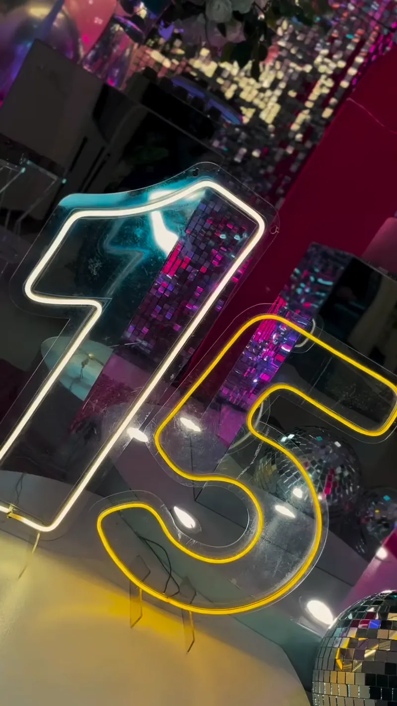 Letreiro neon 15 sobre painel de paetê em festa de debutante